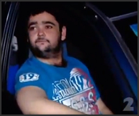 Pixel-art still of a bloke in a blue shirt sitting in the driver's seat of a car at night, waiting.